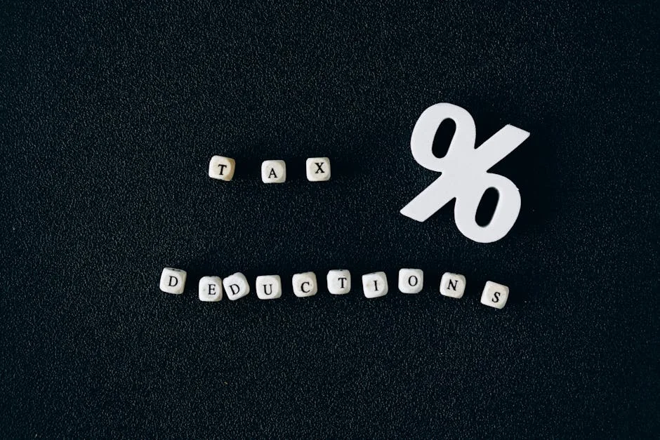 Conceptual image of tax deductions with alphabet blocks and percent symbol on black surface.